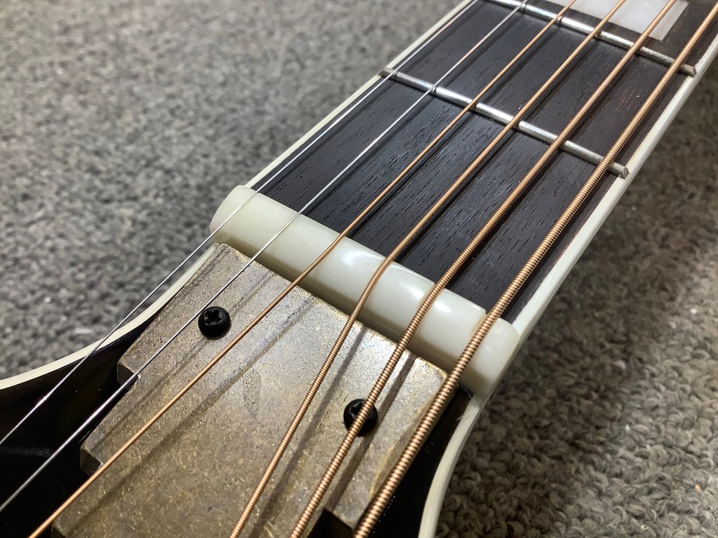 Cejilla de guitarra acústica con las cuerdas instaladas mostrando el terminado al alto brillo