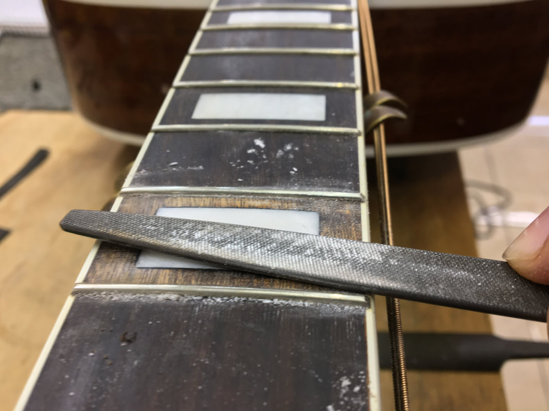 Foto de diapasón de guitarra en reparación con una lima