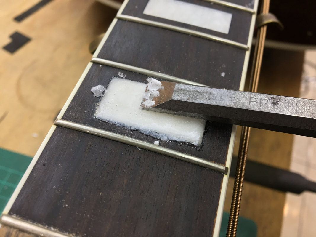 Foto de un formón cortando la incrustación de un diapasón de guitarra
