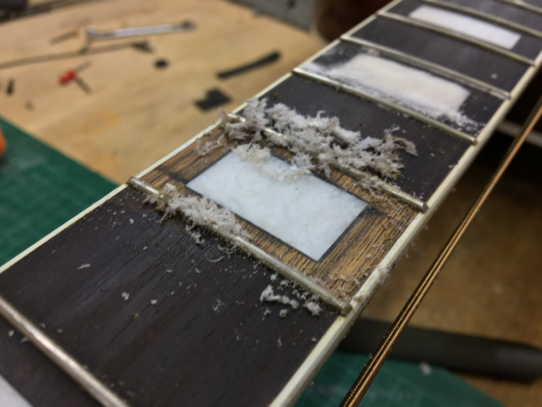 Foto de una incrustación del diapasón de guitarra siendo reparada