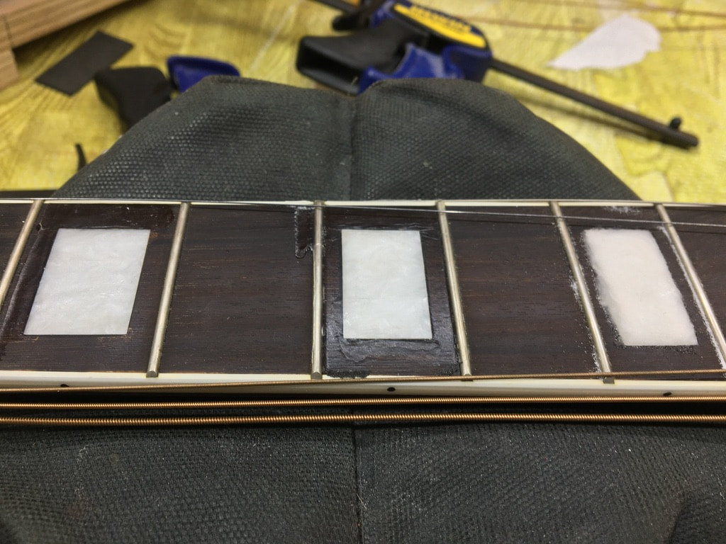 Foto de diapasón de guitarra con incrustaciones en reparación