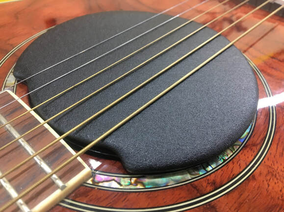 Close-up of guitar soundhole with humidity control device